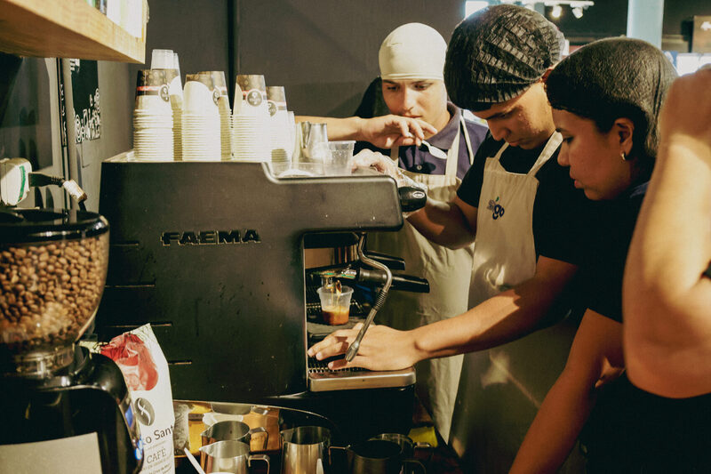 Alumnos con delantal practican en la máquina de espresso de la barra del salón
